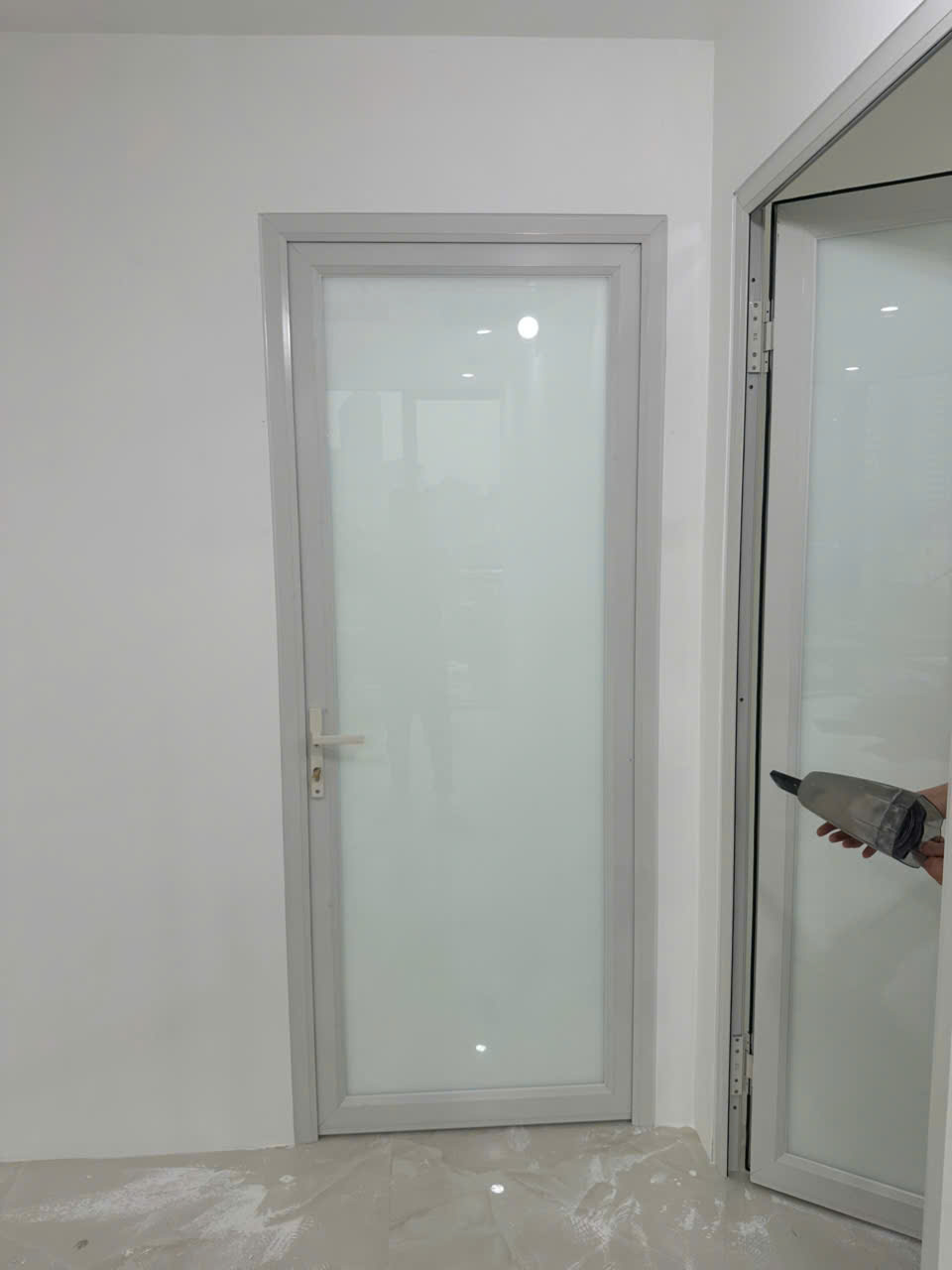 Cửa kính khung nhôm màu trắng mờ lắp trong nhà với tay nắm và bản lề hiện đại